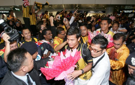 Muslim Ahmad, right in the middle with the bouquet, going through the crowd of fans at KLIA.