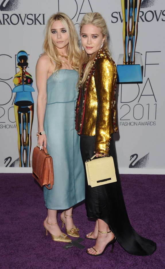Ashley Olsen (left) in a long blue dress by The Row, and Mary-Kate in a golden Chanel jacket and a black skirt by The Row