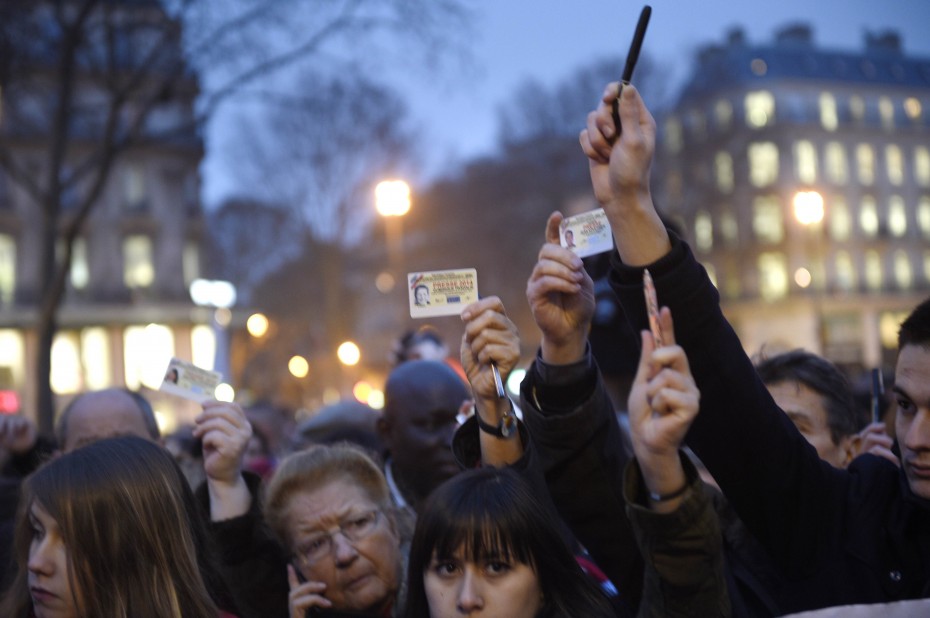 Journalists raising their press cards while others hold up pens at Place de la Republique. -- Photo by AFP